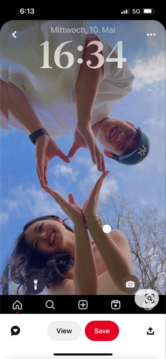 two people making a heart shape with their hands on top of each other in front of a blue sky