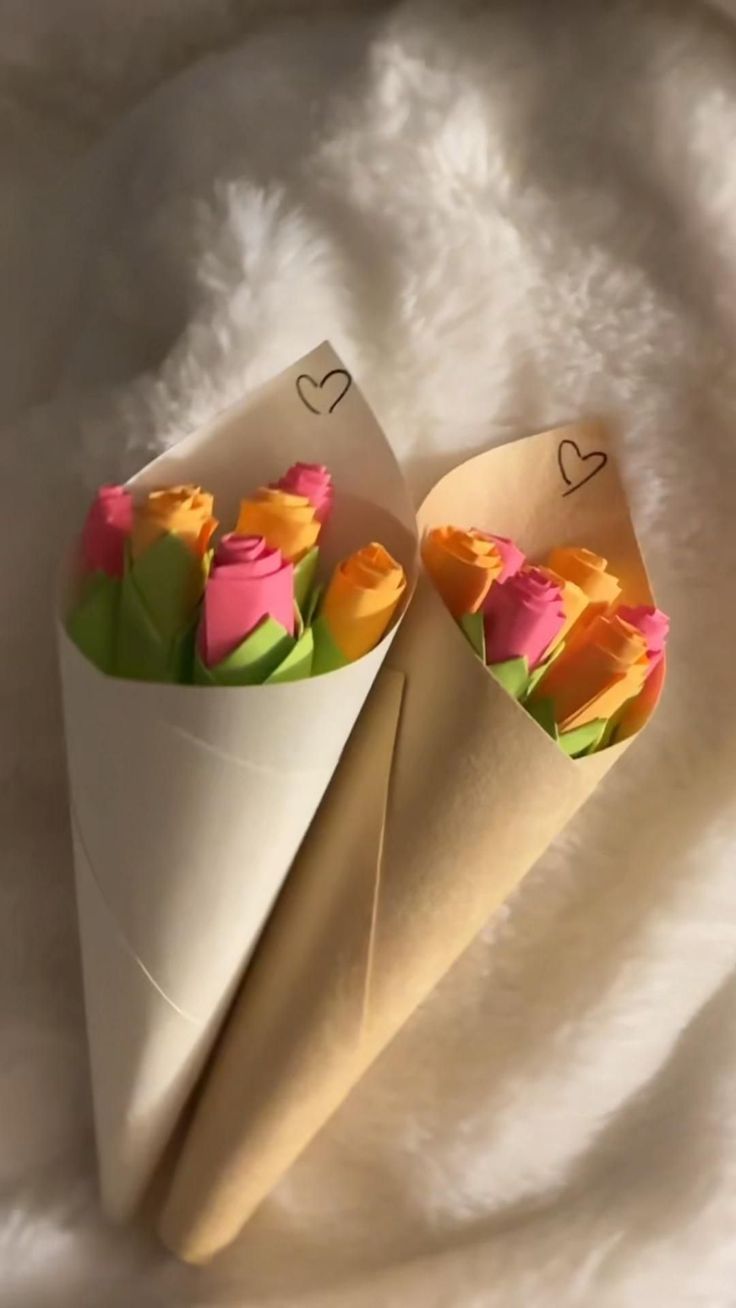 two paper cones with flowers in them on a white blanket