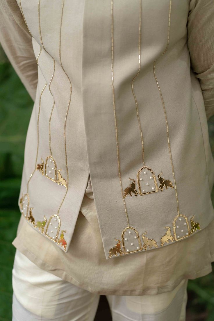 the back of a woman's jacket with embroidered designs on it and gold trimmings