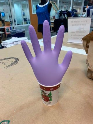 a purple plastic hand sitting on top of a table