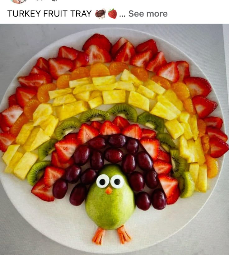 a white plate topped with fruit and a turkey made out of grapes, strawberries