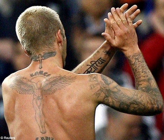 a shirtless man with tattoos on his back and arms raised up to the sky