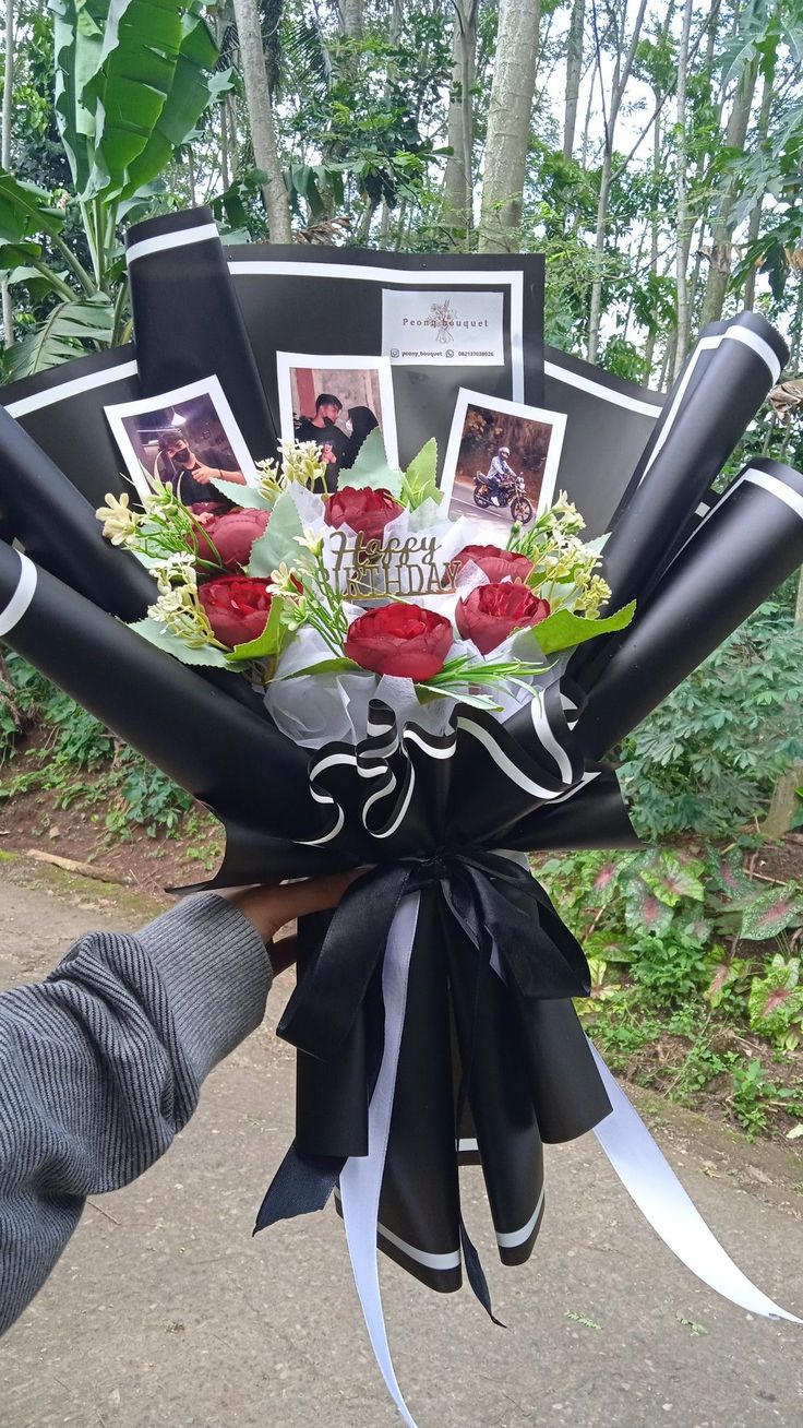 a bouquet of flowers is being held by someone's hand with pictures on it