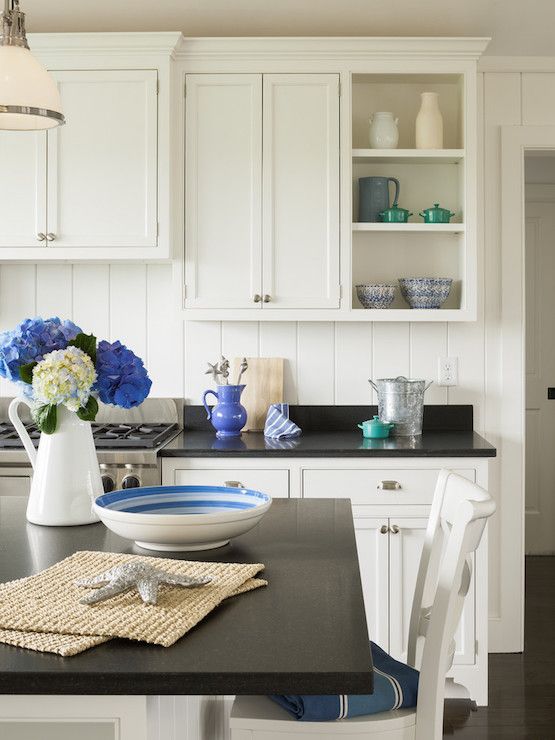 a kitchen with white cabinets and blue flowers on the counter top in front of it