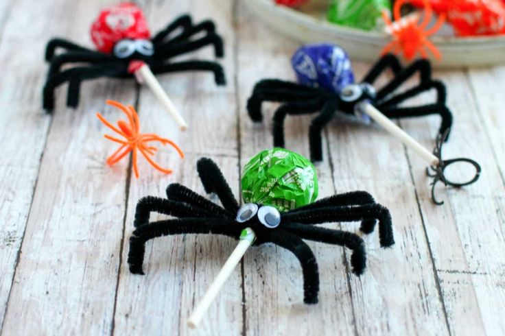 four spider lollipops sitting on top of a wooden table