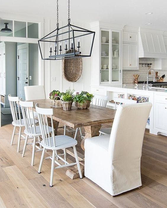 a dining room table and chairs in a kitchen with white cabinets, wood flooring and an island