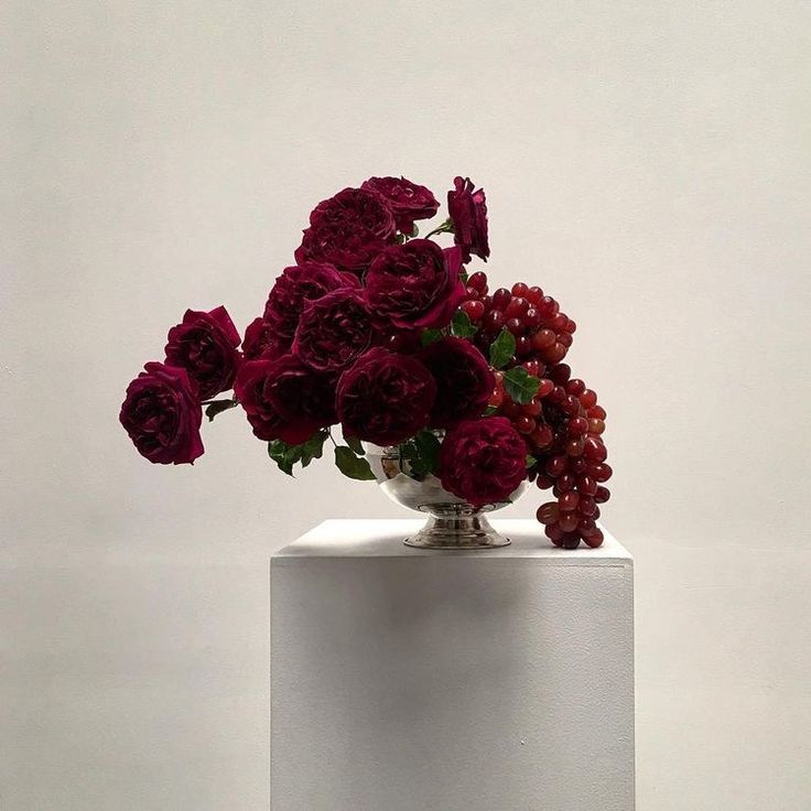 a white vase filled with red flowers on top of a table