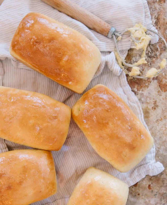 four loaves of bread sitting on top of a cloth next to a rolling pin