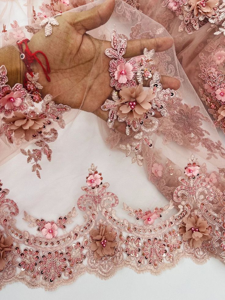 a woman's hand is shown with pink flowers on her wedding dress and veil