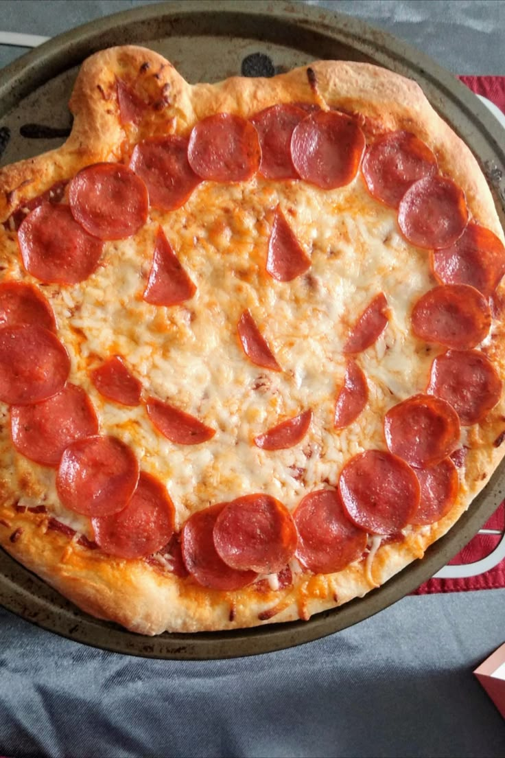 a heart shaped pepperoni pizza sitting on top of a pan