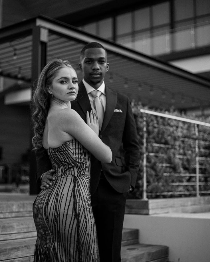 a man and woman standing next to each other in front of a building with stairs