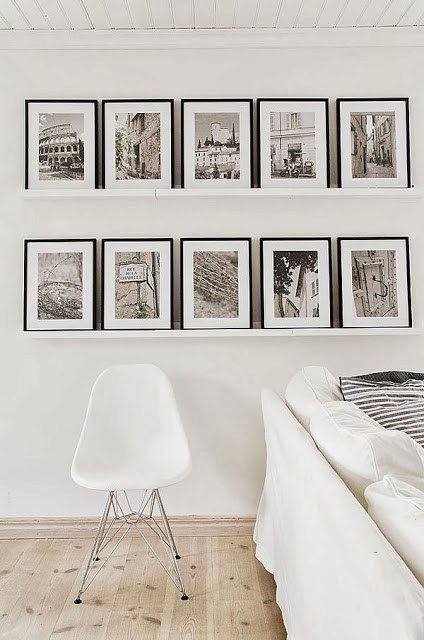 a living room with white furniture and pictures on the wall