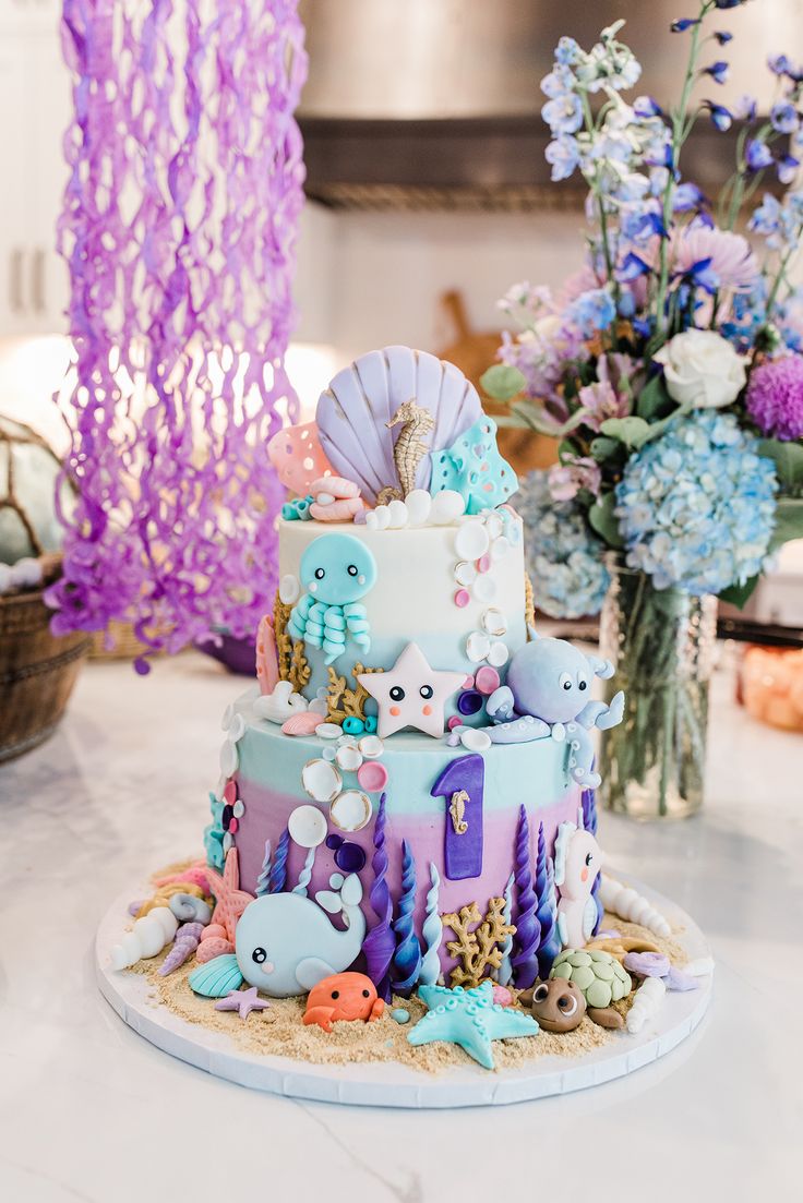 a three tiered cake decorated with sea animals and seashells on a table