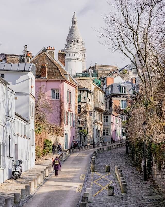 a person riding a bike down a cobblestone road in front of some buildings