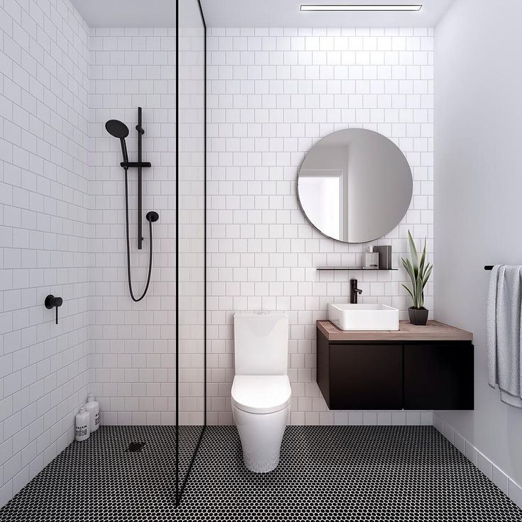 a modern bathroom with black and white tiles on the floor, toilet, shower head, sink, mirror and towel rack