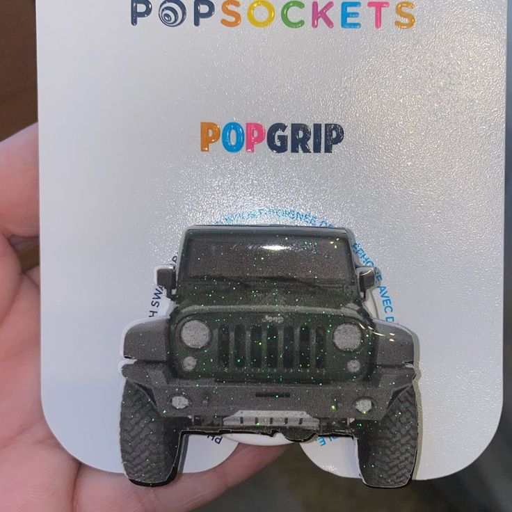 a person holding up a plastic card with a jeep on it's front and the words popsockts popgrip