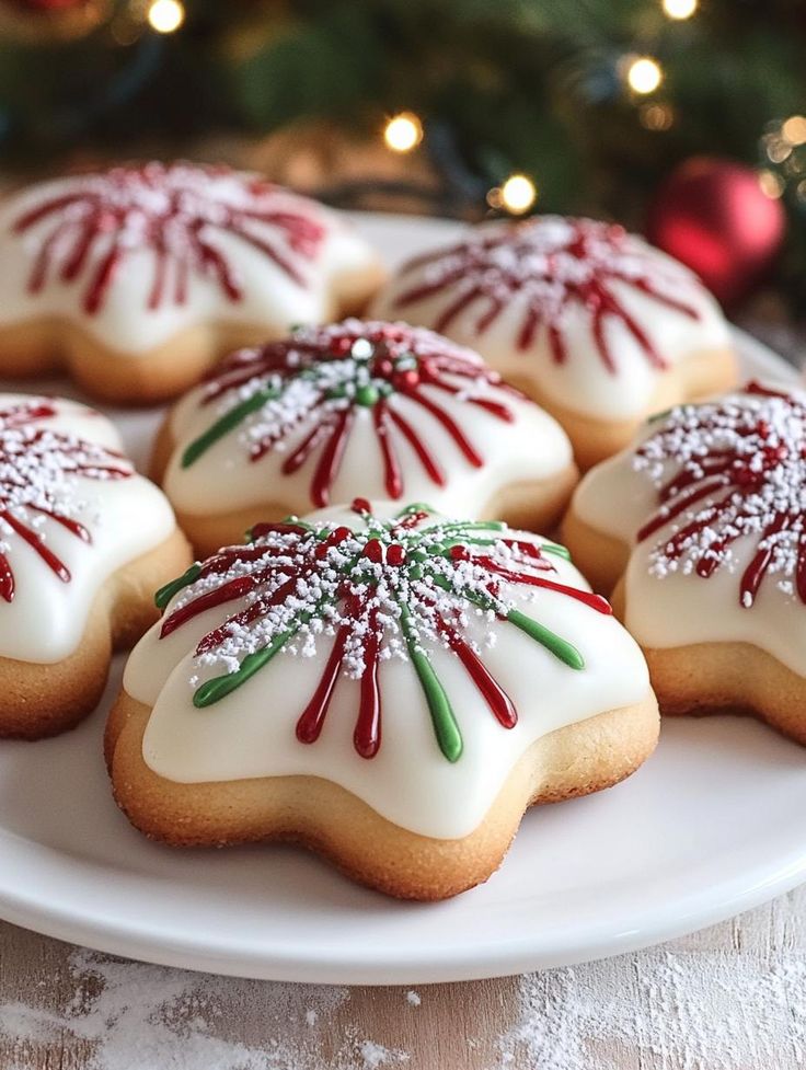 decorated cookies on a white plate next to a christmas tree