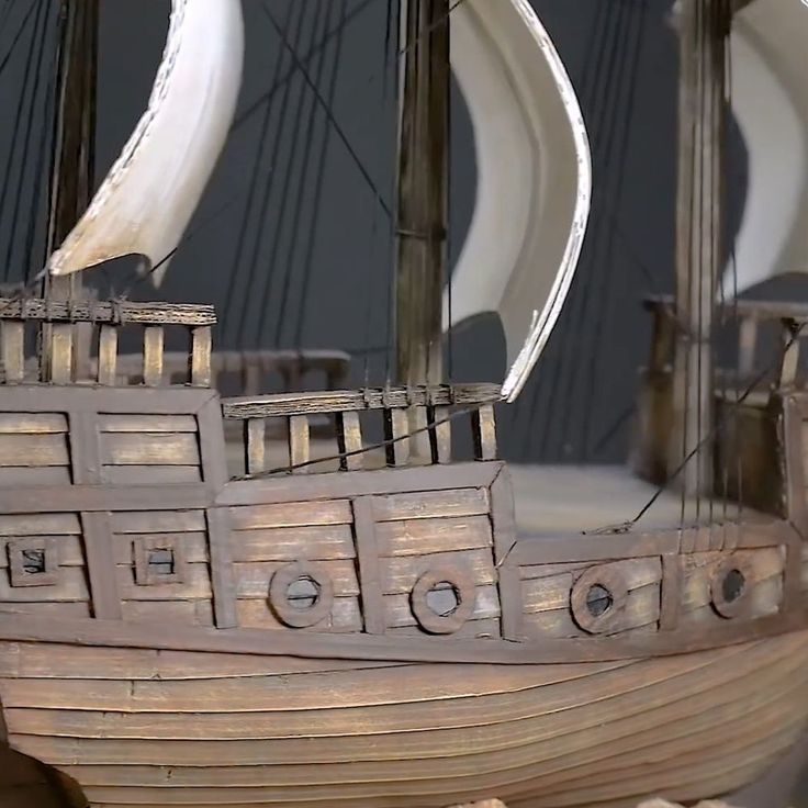 a wooden model ship with white sails