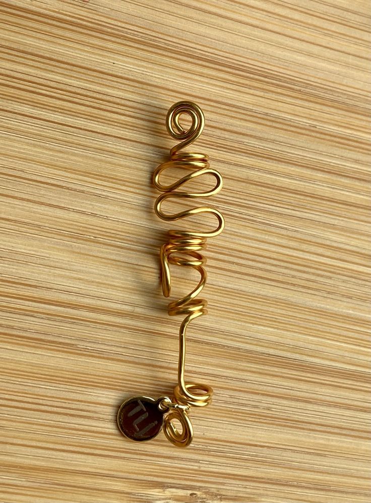 The KISMET Artistic Gold Wire-Wrap SISTERLOCK Jewel is a trend-setting design style of traditional gold-plated wire wrapped in an artistic, abstract form. The Sisterlock-sized Jewel measures 2.75 to 3.25 mm coil wrap. This jewel is the perfect compliment to other gold pieces in all collections due to its simple design. This is a unique design with loops, squared off angles and swirls, exuding a magnificent shine with this non-tarnish gold wire! It will not change color or peel. This jewel is a h Artistic Gold Spiral Jewelry, Artsy Gold Wire Wrapped Jewelry, Gold Bohemian Wire Jewelry, Artsy Gold Jewelry With Unique Design, Bohemian Gold Wire Jewelry, Artsy Gold Copper Jewelry, Adjustable Spiral Gold Jewelry, Unique Gold Wire Jewelry, Gold Copper Hand Wrapped Jewelry