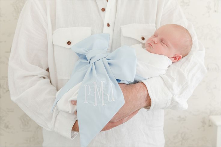 a man holding a baby wrapped in a blue bow