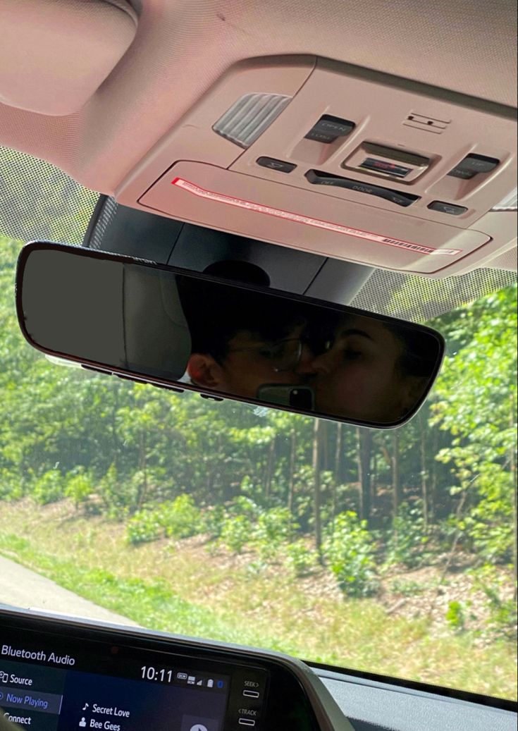 two people are seen in the rear view mirror of a car