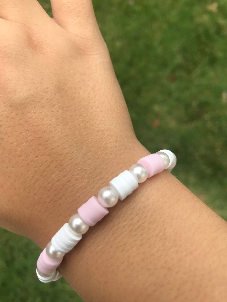 a woman's hand wearing a pink and white bracelet