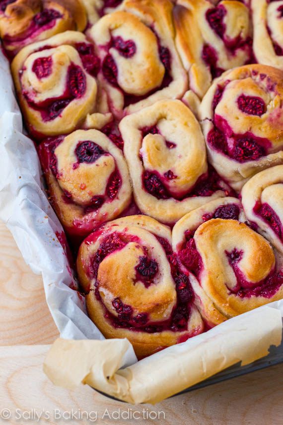 a pan filled with raspberry rolls sitting on top of a wooden table