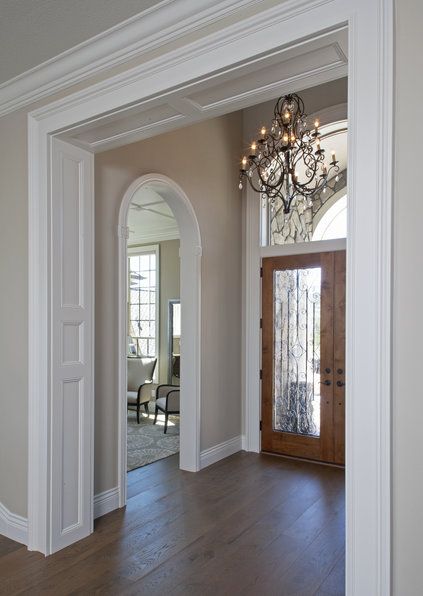 an empty entry way with a chandelier and wooden floors in front of it