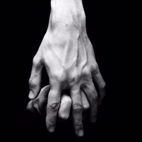 two hands holding each other in the dark