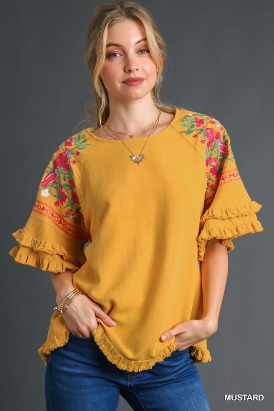 Umgee Linen blend top with layered flounce sleeves and embroidery. Fringe hemmed. Super cute blouse! Color: Mustard Sizes: S-M-L True to sizeOur model is 5' 9" wearing a small 55% Linen, 45% Cotton, importedO5/K7342 Bohemian Ruffle Tops For Brunch, Bohemian Tops With Flutter Sleeves For Brunch, Bohemian Flutter Sleeve Top For Brunch, Embroidered Cotton Blouse With Flutter Sleeves, Bohemian Tops With Floral Embroidery And Flutter Sleeve, Spring Embroidered Tops With Flutter Sleeves, Bohemian Ruffle Sleeve Tops For Spring, Cotton Blouse With Flutter Sleeves And Floral Embroidery, Cotton Blouse With Flutter Sleeves For Fall