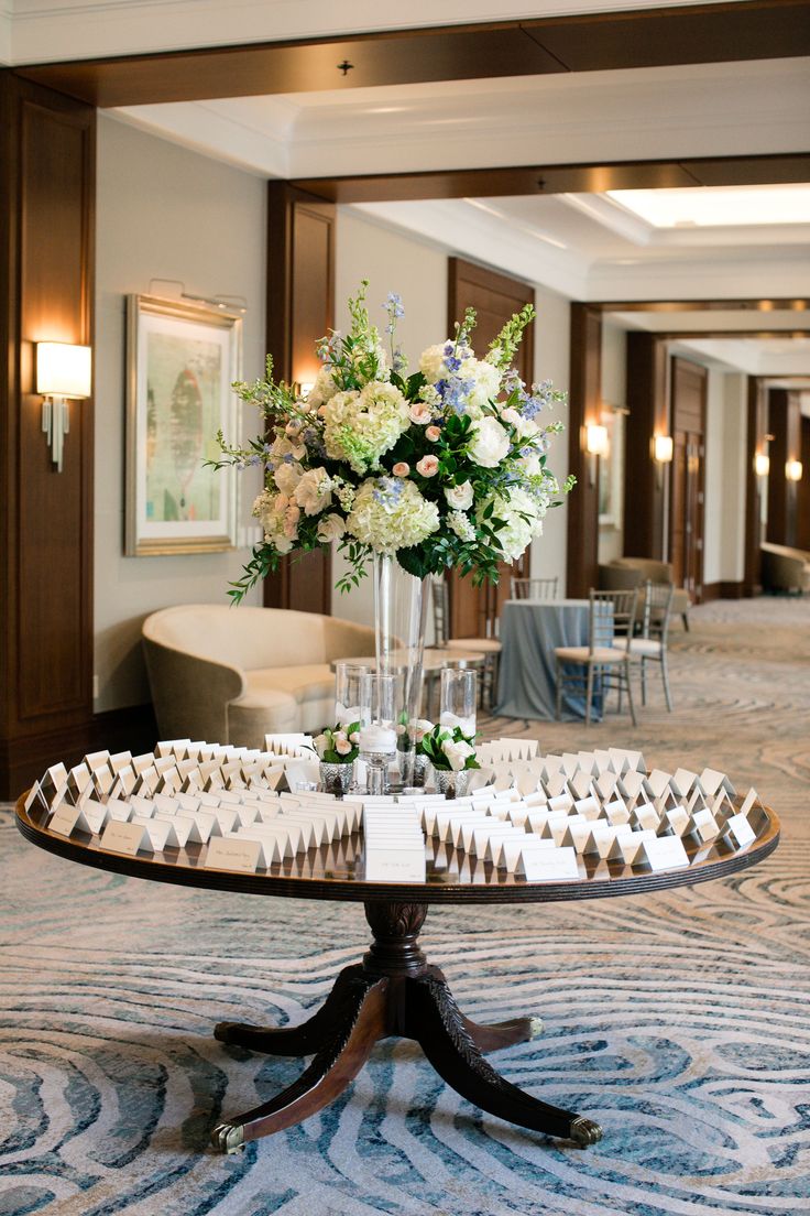 a table with flowers and candles on it in the middle of a large room filled with chairs