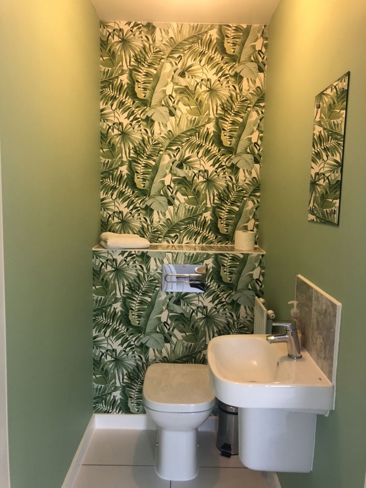 a bathroom with green and white wallpaper, toilet and sink in the foreground