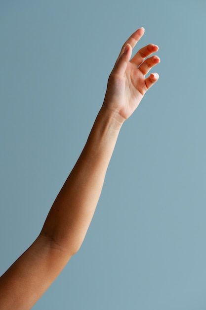 a hand reaching up into the sky to catch a frisbee