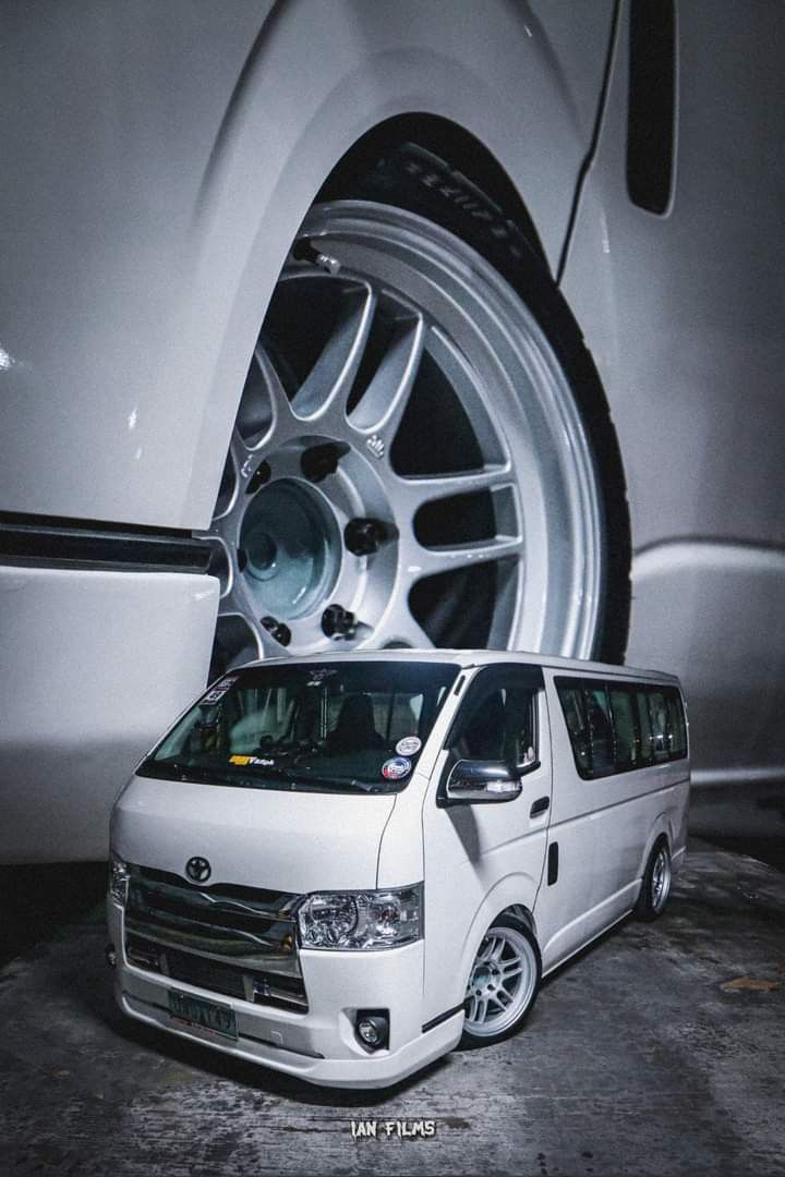 a white van parked in front of a car with its wheels on it's rims