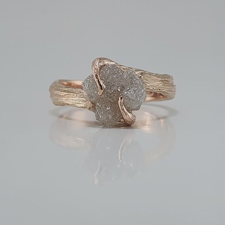 a gold and white diamond ring sitting on top of a table