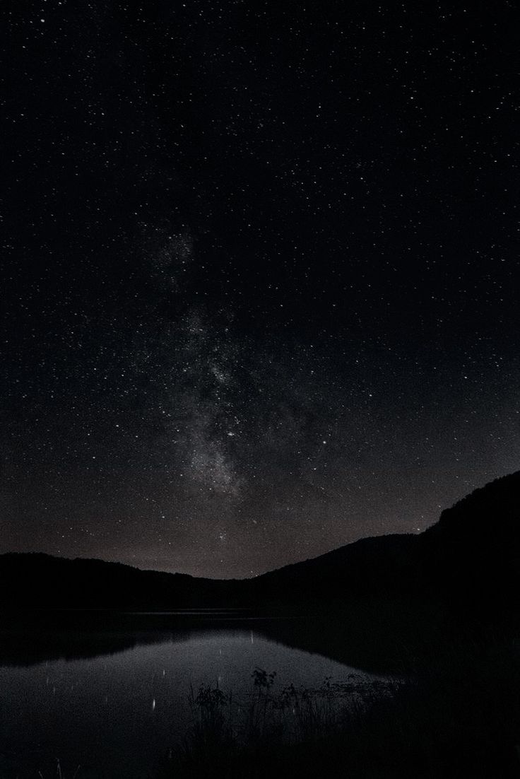 the night sky is filled with stars above a lake