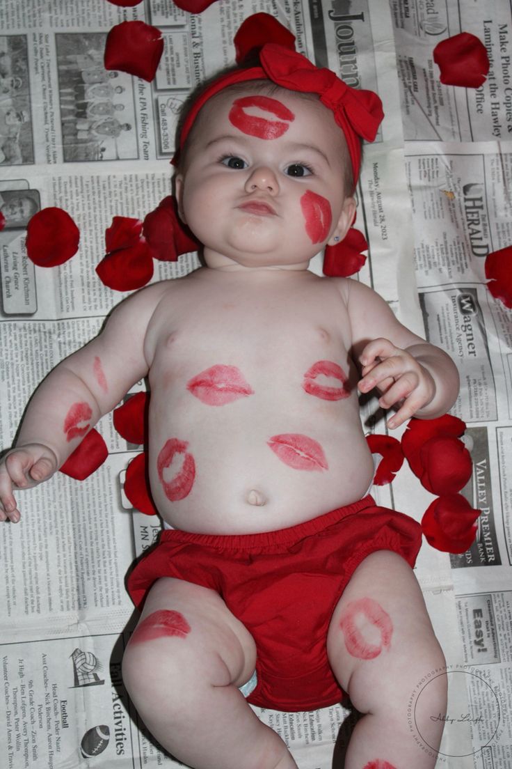 a baby with red lipstick on it's face is laying in front of newspapers