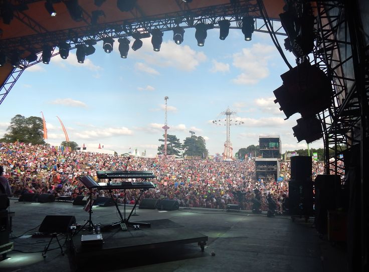 a large crowd is watching a band perform on stage in front of an outdoor concert