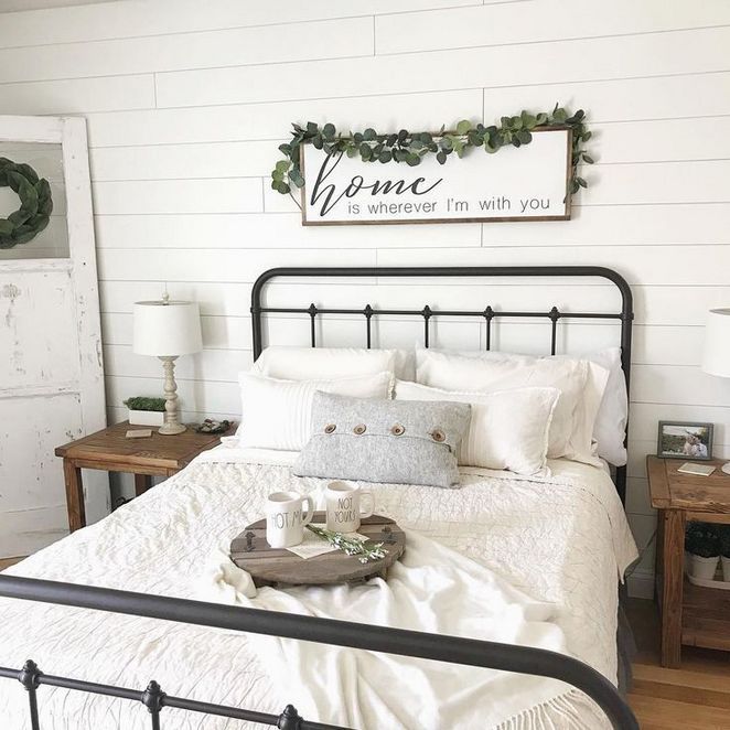 a bed with white sheets and pillows in a bedroom next to a wooden sign that says home