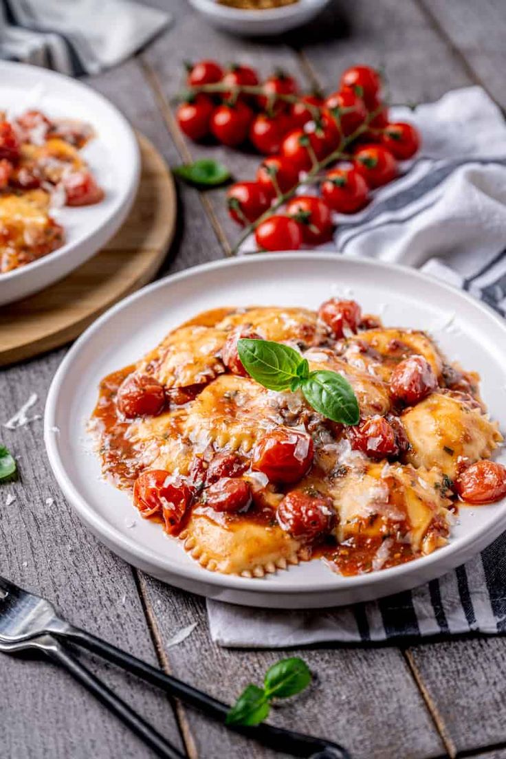 two plates of ravioli with tomatoes and basil