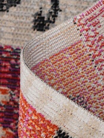 an area rug with different colors and patterns on the floor, including red, orange, black, white and pink