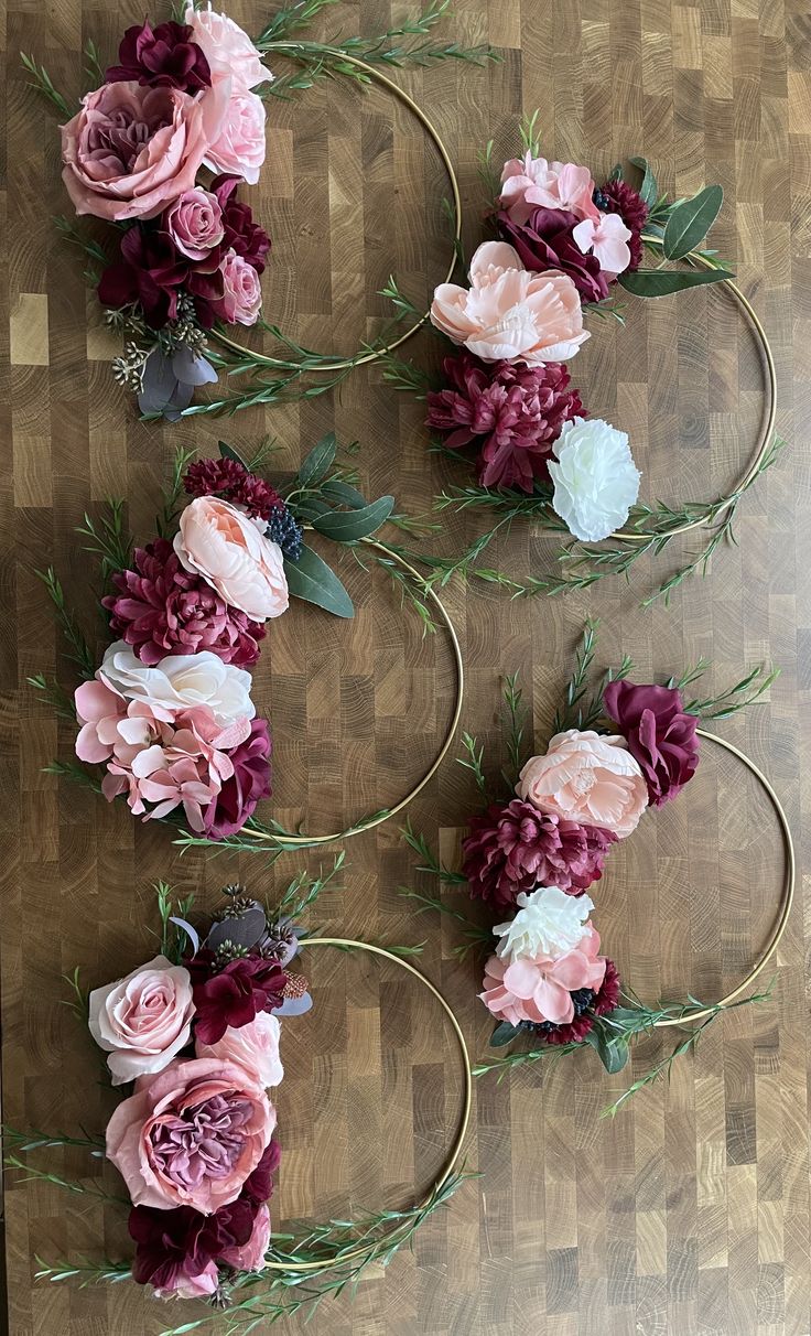 flowers are arranged in the shape of hoop vases on a wooden table with greenery