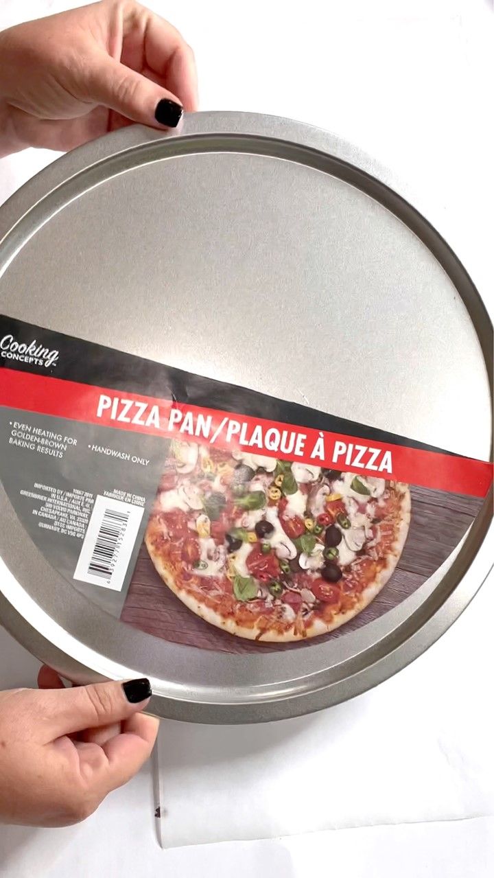 a pizza pan with a piece of pizza in it's middle being held up by two hands