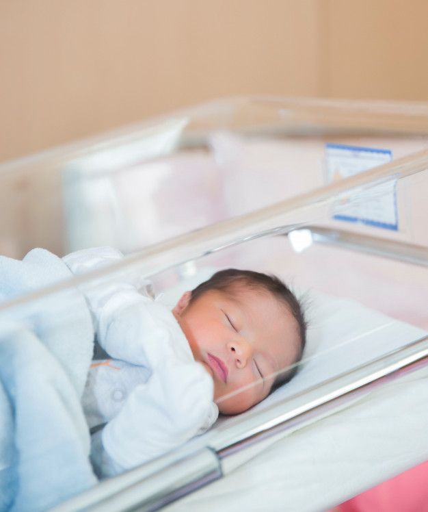 a baby is sleeping in a clear crib with its eyes closed and head tucked under a blanket