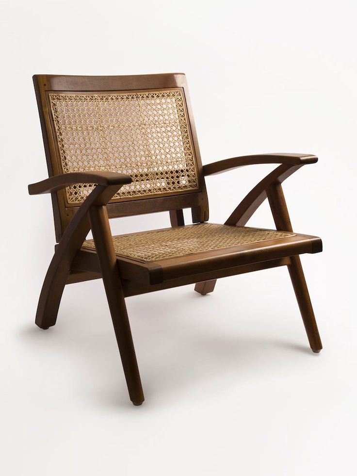 a wooden chair with wicker back and arm rests against a white background in the foreground