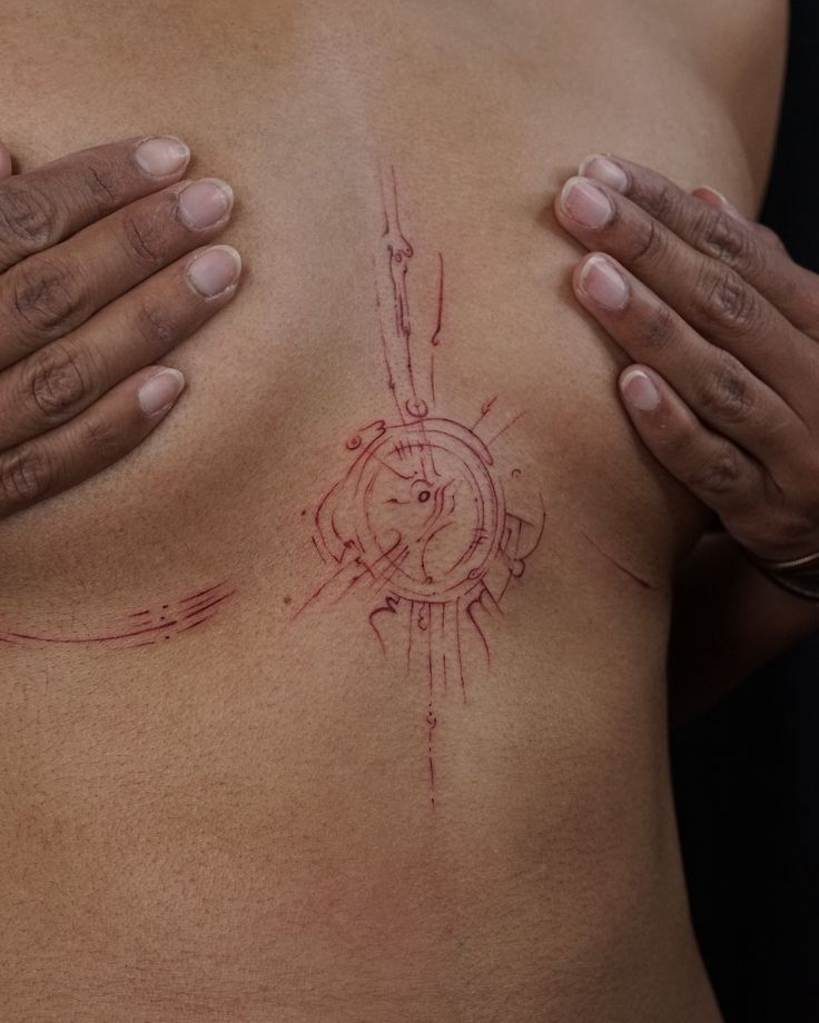 a close up of a person's chest with tattoos on it and their hands