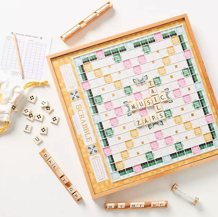 a scrabble board with letters and dices next to it on a white surface