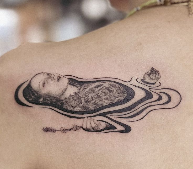 a woman's back with a tattoo on her shoulder and an image of a man