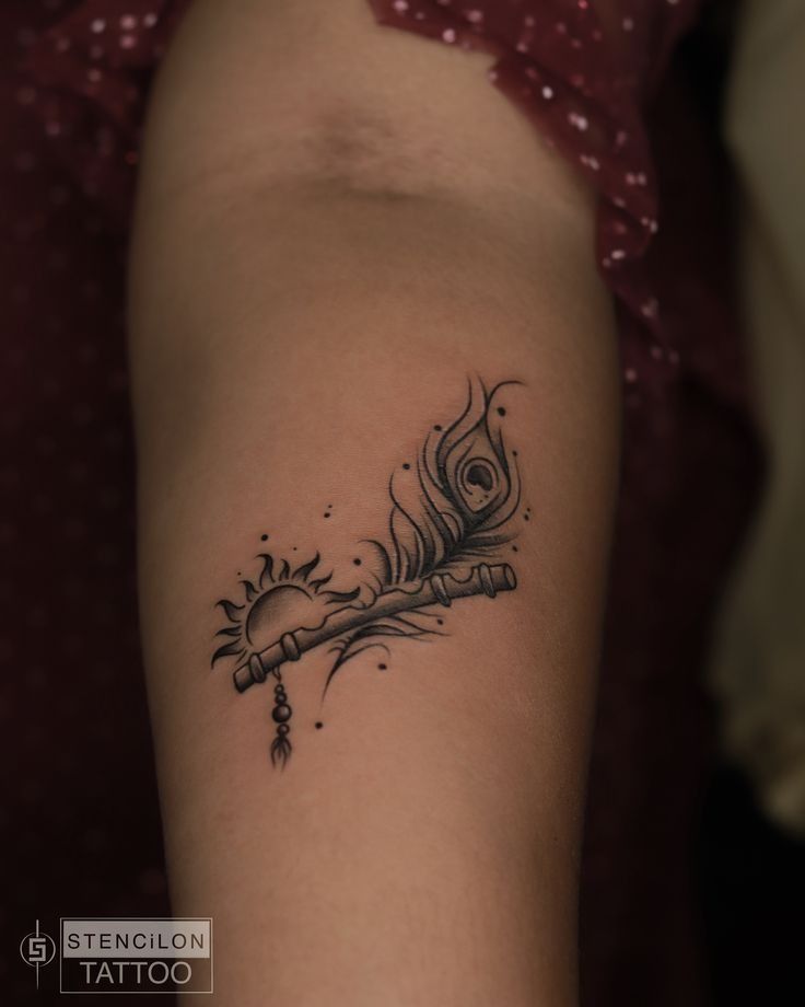 a woman's arm with a tattoo on it that has a feather and an arrow