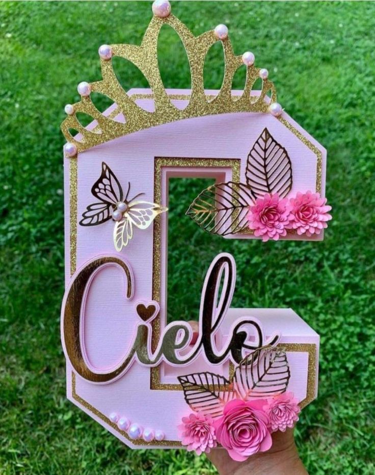 a hand holding up a pink and gold letter that says celeb with flowers on it